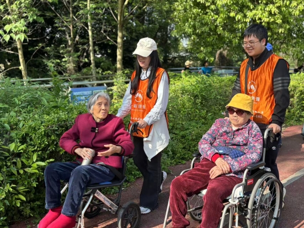 志愿者推着长者在公园散步
